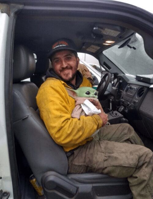 Oregon firefighter holds Baby Yoda in his vehicle.