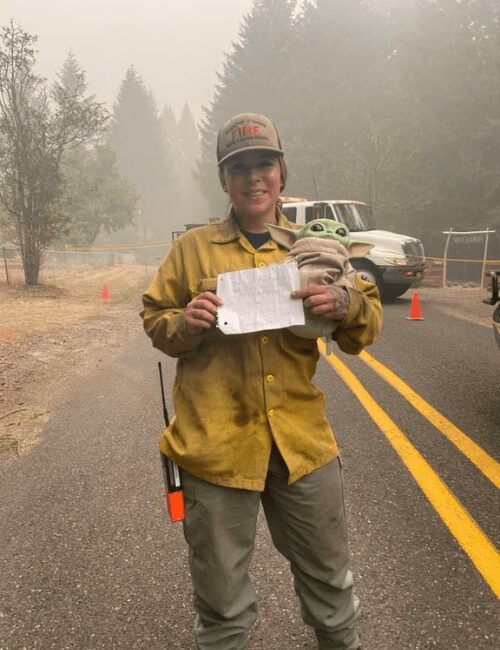 Oregon firefighter holding Baby Yoda and Carver's hand-written note.