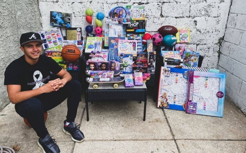 Angel Ortero sitting in front of the toys he bought to donate to kids in DR.